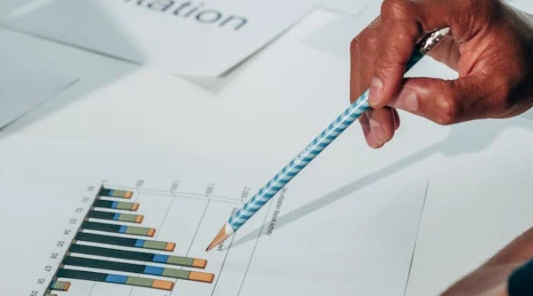 hand with pencil showing leads on graph